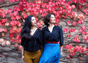 La mezzo-soprano Salma Sadakla et la soprano Inès Cañameras posent devant un mur recouvert de feuilles 
