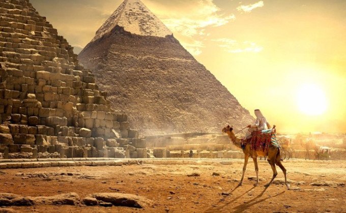Un homme à dos de dromadaire devant les pyramides de Giza