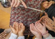 Une médiatrice verse de la fleur d'oranger grace à un aspersoir dans les mains de plusieurs enfants