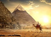 Un homme à dos de dromadaire devant les pyramides de Giza